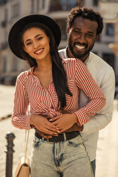 istock Happy man hugging girlfriend behind her back and smiling 1165075854