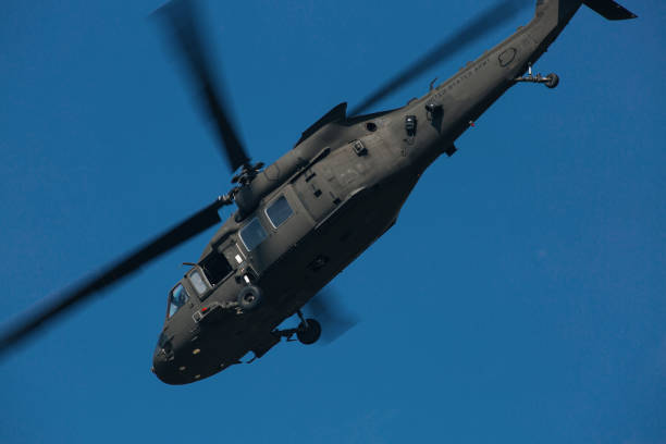 istock Military helicopter in the sky makes a turn behind dark sky 1165077137