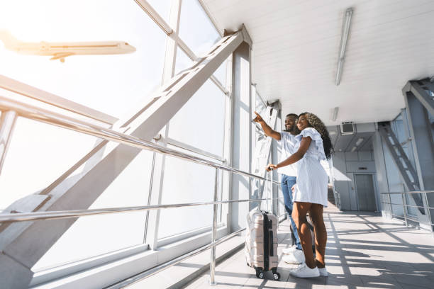 istock Loving african couple looking at flying plane in sky 1165079007