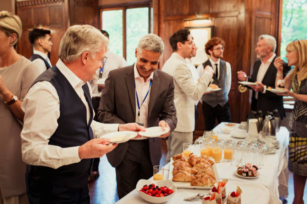 Networking with Breakfast Business people plating up complimentary food while at a business conference. The group is talking and eating while networking. continental breakfast photos stock pictures, royalty-free photos & images