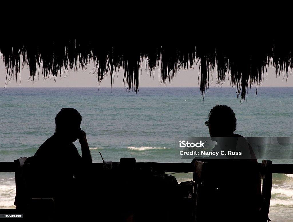 男性のパラパでは、リラックスしたシルエット、トロピカルな雰囲気の屋外バー - 打ち寄せる波のロイヤリティフリーストックフォト