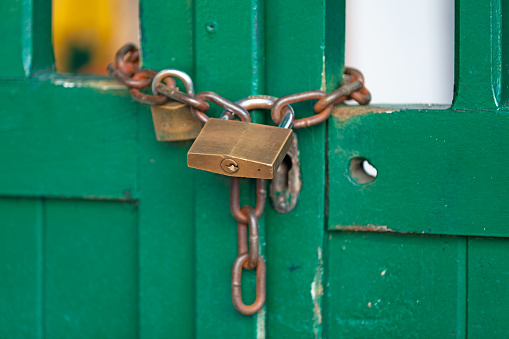 Close-up on a chain and a padlock closing a door.
