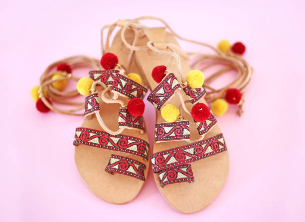 bohemian leather sandals with red tassel and pom pom - gladiator sandals - pink background still life of bohemian leather sandals with red tassel and pom pom - gladiator sandals - pink background gladiator shoe stock pictures, royalty-free photos & images