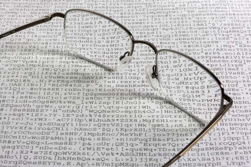 Reading glasses against a sheet of unreadable meaningless text - gibberish produced by a faulty software