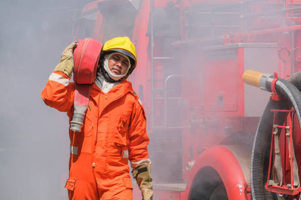 istock Firefighters training, Team practice to fighting with fire in emergency situation. A fireman carry a water hose run through flame 1165095532