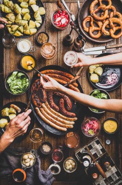 istock Octoberfest dinner table with beers, sausages, peoples hands with snacks 1165098266