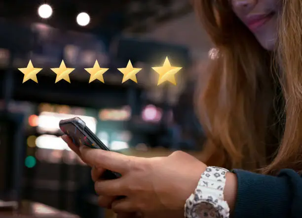 Photo of Millennial woman submitting star rating feedback on mobile device after internet shopping experience