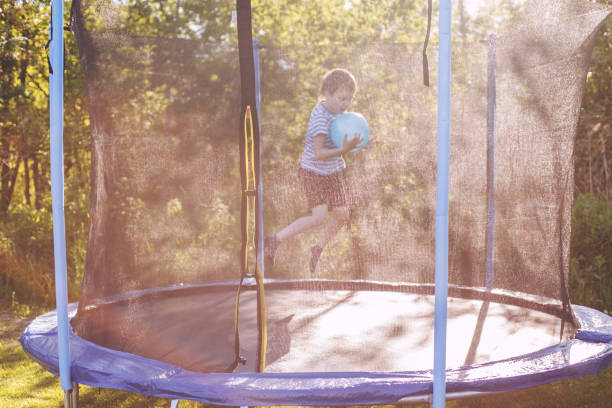 istock boy jumping on trampoline. child playing with a ball on a trampoline 1165098331