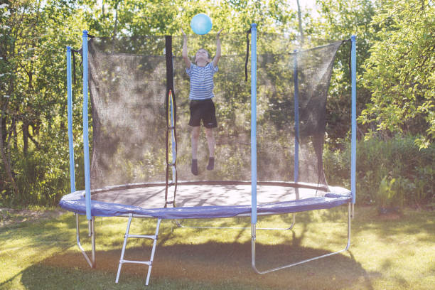 istock boy jumping on trampoline. child playing with a ball on a trampoline 1165098367