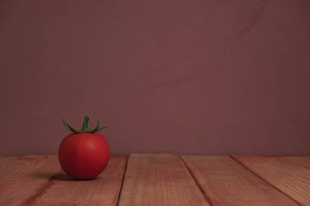 istock Fresh alone tomato on a red wooden table beautiful purple background. 1165098481