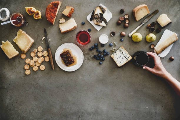 istock Cheeses, honey, fruit, nuts, crackers and wineglass in female hand 1165098866