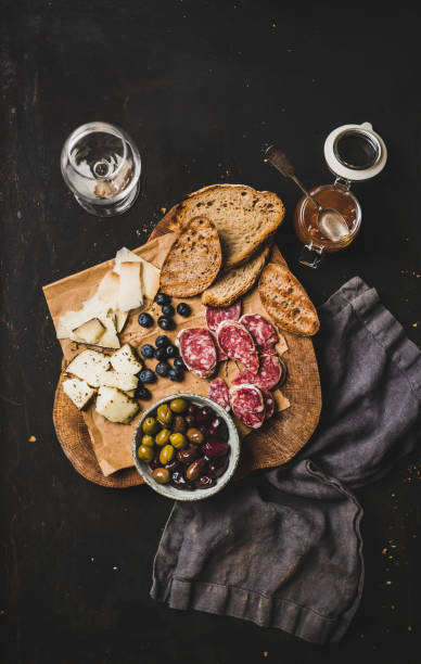 vino bianco e snack sullo sfondo nero, vista dall'alto - wine cheese food salami foto e immagini stock