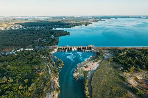 Dam at reservoir with flowing water, hydroelectricity power station, aerial panoramic view.