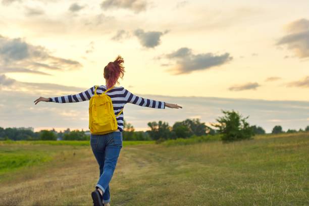 istock Young girl with yellow backpack, her back with open hands 1165101452