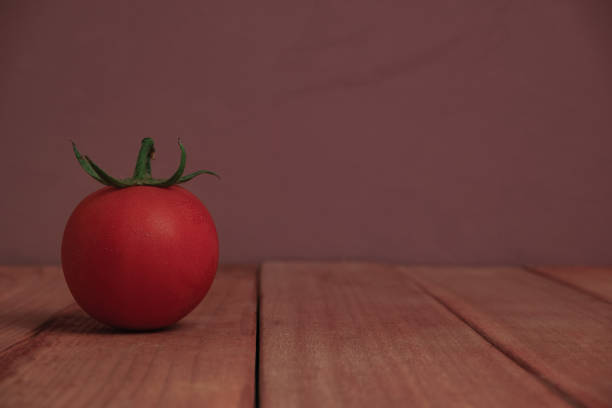 istock Fresh alone tomato on a red wooden table beautiful purple background. 1165101510