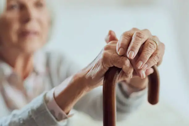 Cropped shot of a senior woman holding onto her walking stick while in the living room of a nursing home