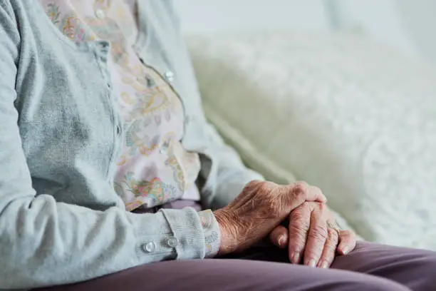 Cropped shot of an unrecognizable senior woman sitting on the sofa while in the living room of a nursing home