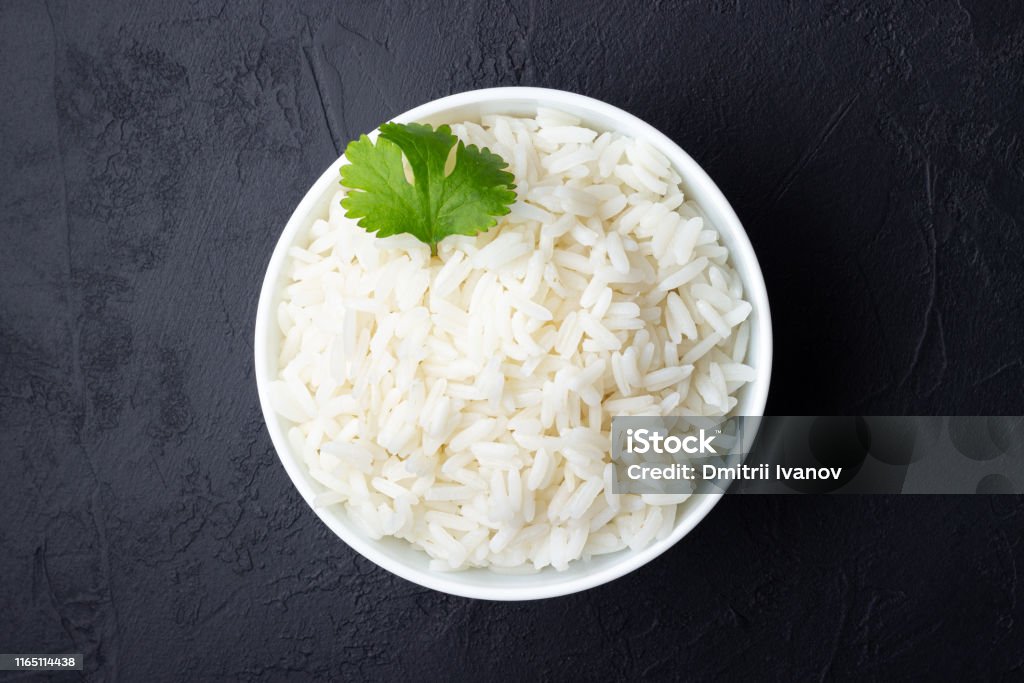 Boiled rice in a bowl. Boiled rice in a bowl on black stone background. Rice - Cereal Plant Stock Photo