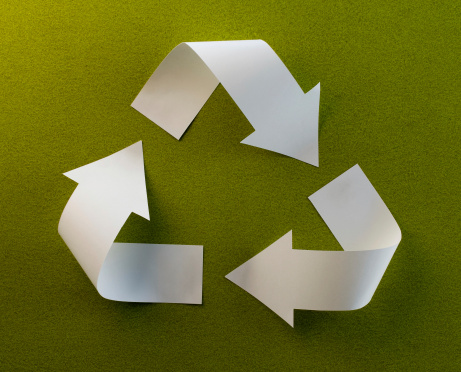 Recycle symbol from paper on green background.
