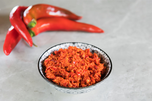 Paprika spice in a small dish on a rustic wooden grey table. Close up view with copy space. Stock photo.