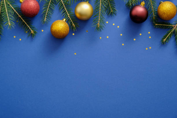 istock Christmas frame top border with fir tree branches, confetti, gold and red decorations, balls on blue background. Christmas or New Year banner mockup template with copy space. Flat lay, top view. 1165123911