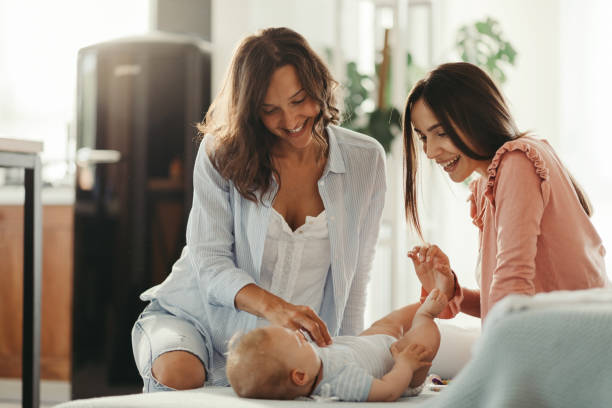 istock Two happy women playing with a baby on the bed. 1165125980