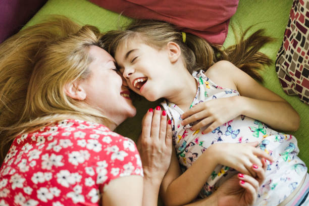 istock Mother and daughter cuddling together on couch 1165126917
