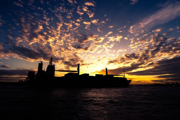 logistisches frachtschiff - silhouette mit sonnenuntergang hintergrund - industrial ship audio stock-fotos und bilder