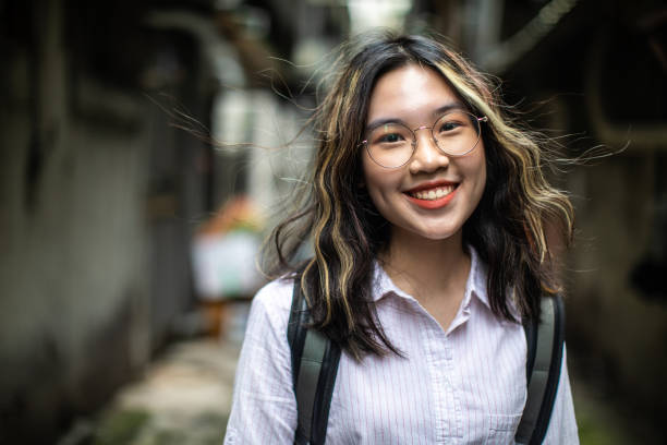 Portrait of urban, smiling  Asian female student outdoor with backpack, wearing eyeglasses
