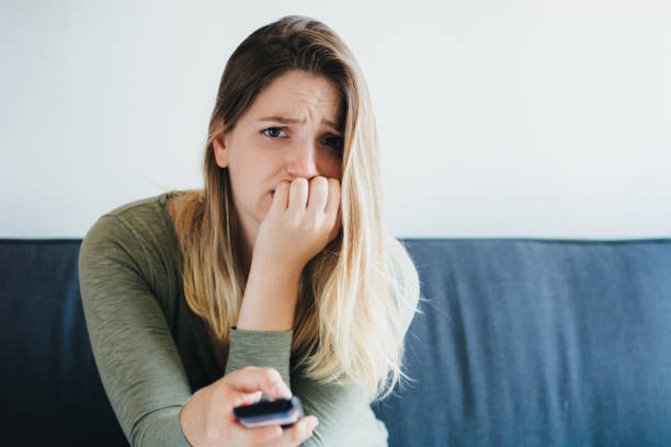 istock Beautiful woman  sitting on sofa and watching tv 1165129966