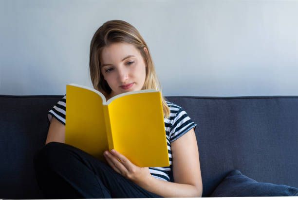 istock Woman reading a book at home 1165129974