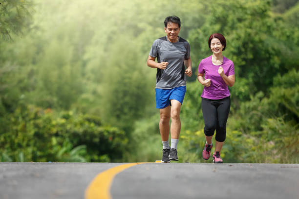 exercice asiatique de jogging de couples d'âge moyen en stationnement - couple dâge mûr photos et images de collection