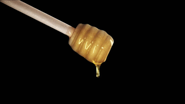 istock Honey dripping from honey dipper on black background 1165131779