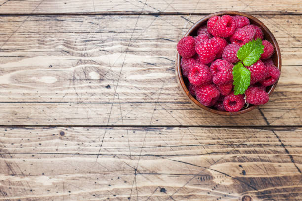 istock Fresh red raspberry berries in a wooden plate. 1165133592