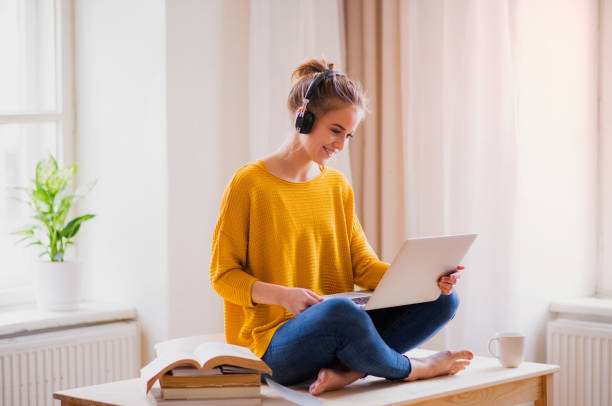 istock A young female student sitting at the table, using headphones when studying. 1165137128