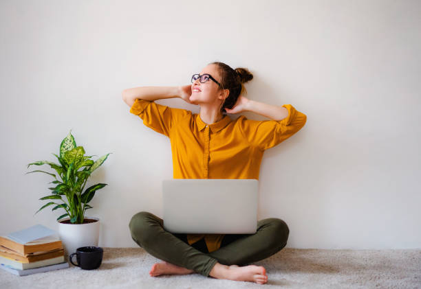 una giovane studentessa seduta sul pavimento usando il laptop quando studia. - floor sitting foto e immagini stock