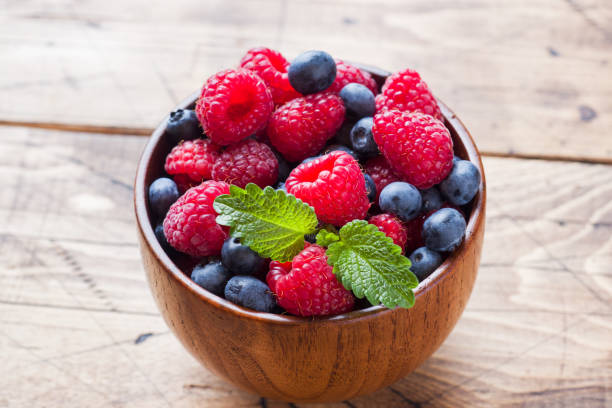 istock Fresh raspberries and blueberries in a wooden plate. 1165138791