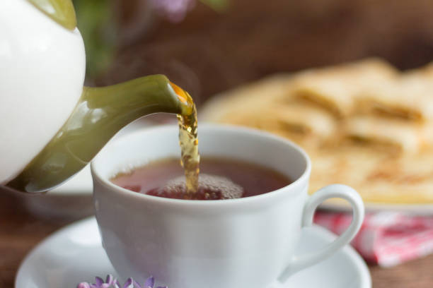 frisch gebrühter tee wird in eine tasse tee gegossen - english breakfast tea stock-fotos und bilder