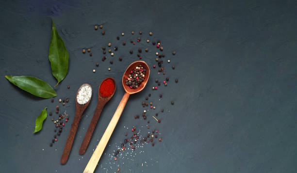 Wooden spoons with spices on blue background.