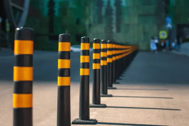 A row of yellow barriers on the road, separating the traffic lines and the pedestrian zone