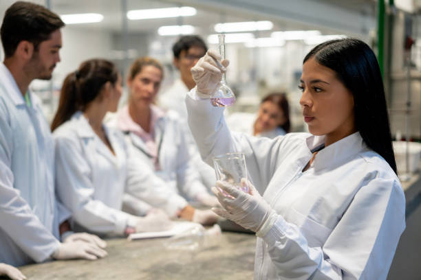istock Latin american student mixing liquids in laboratory flasks 1165145541