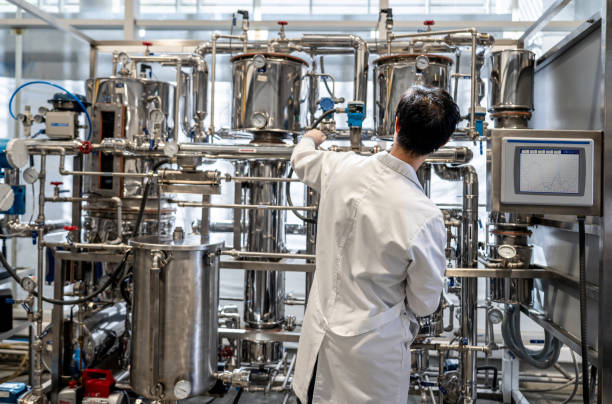 vista posteriore dello studente maschio che lavora al laboratorio di processo distillando liquidi - industria chimica foto e immagini stock