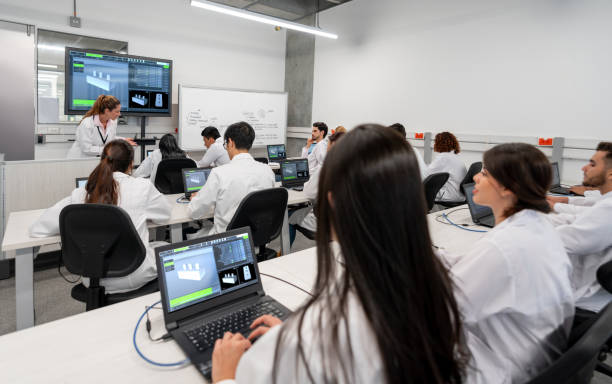 Young students using computers inside technology class at school room - Focus on center guy face