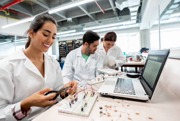 ラボでプロジェクトに取り組む電気技師の学生とバックグラウンドで働く学生のチーム - pliers technician cable electrical equipment ストックフォトと画像