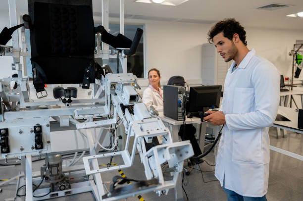 Male students at the mechatronics lab moving an equipment Male students at the mechatronics lab moving an equipment and teacher sitting at background biomechanics stock pictures, royalty-free photos & images