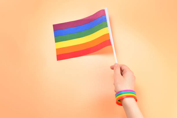 istock LGBT flag in woman hand on orange background. Copy space. 1165146831