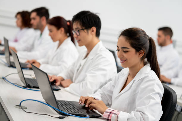 istock Female young beautiful student at computer class working on laptop smiling 1165150573