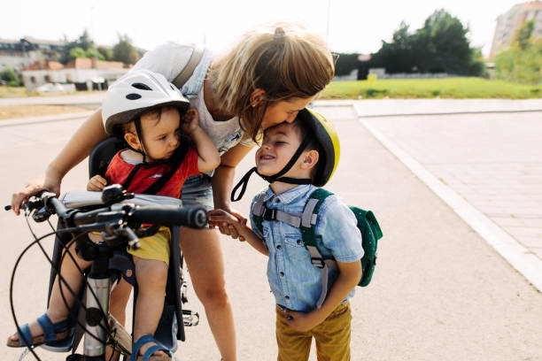 Making a kiss stop to school Smiling boy commute to school with mom and baby brother 6 11 months stock pictures, royalty-free photos & images