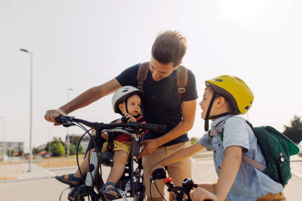 Family on wheels Smiling boy commute to school with dad and baby brother by bicycle 6 11 months stock pictures, royalty-free photos & images
