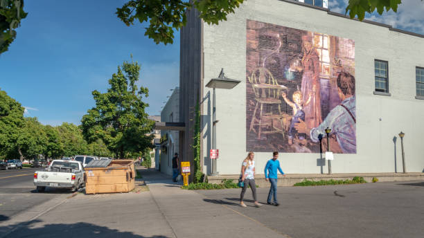 Logan, Utah, United States - August 31, 2018: Mural showing a traditional family with a couple passing by in the foreground taken in Logan, Utah